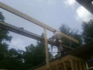 Carpenter setting a ridge beam over a new addition frame — Ice Dam Removal by Roofing Brothers in Northampton